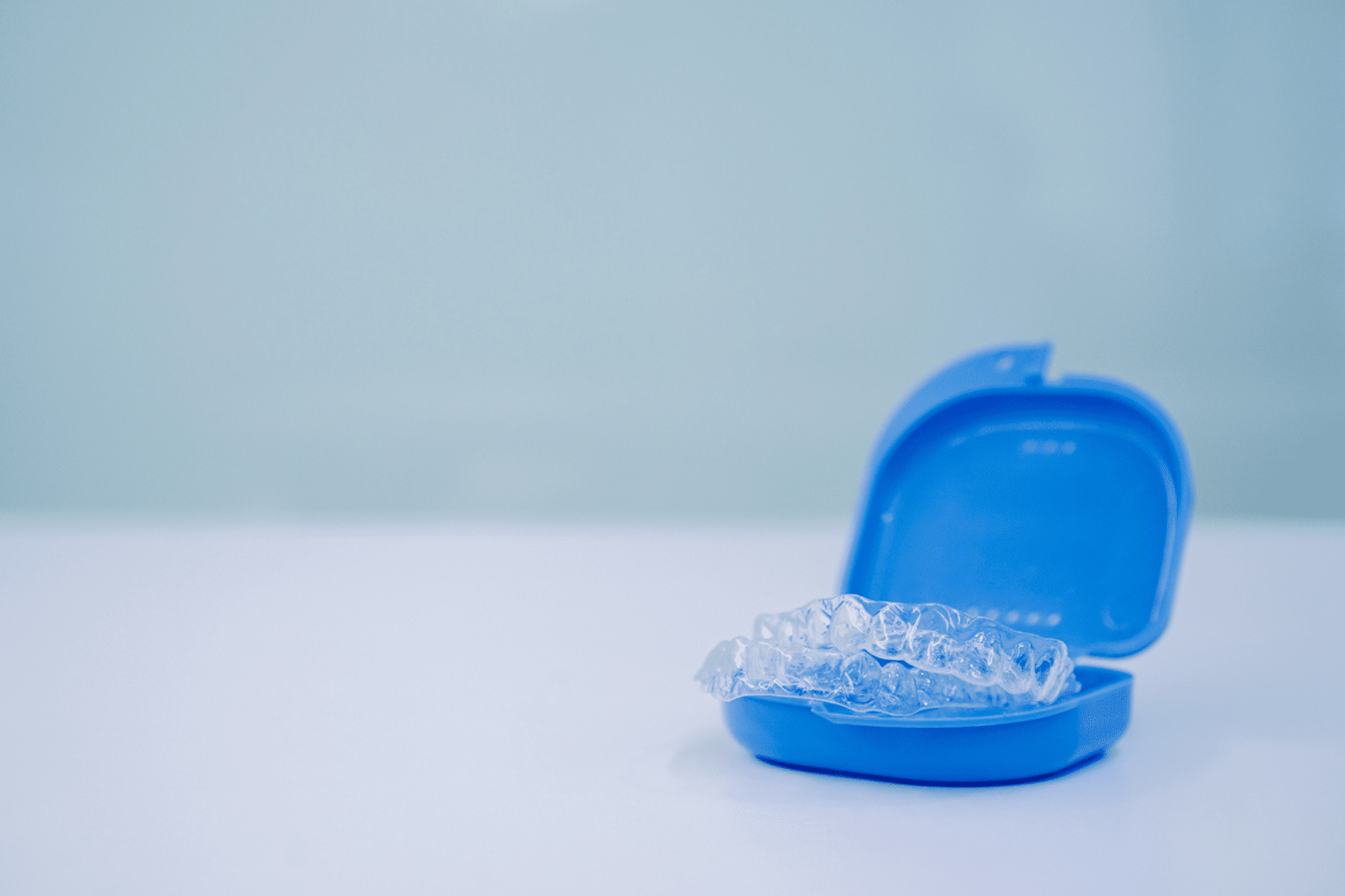 Clear dental aligners resting in an open blue case